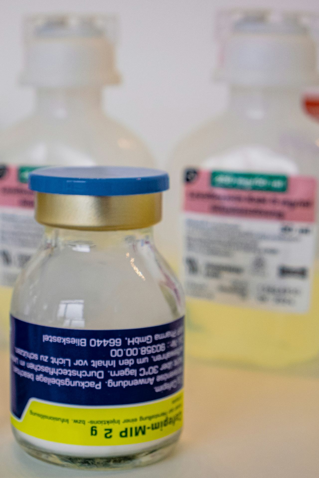 Medical vials with yellow liquid in background